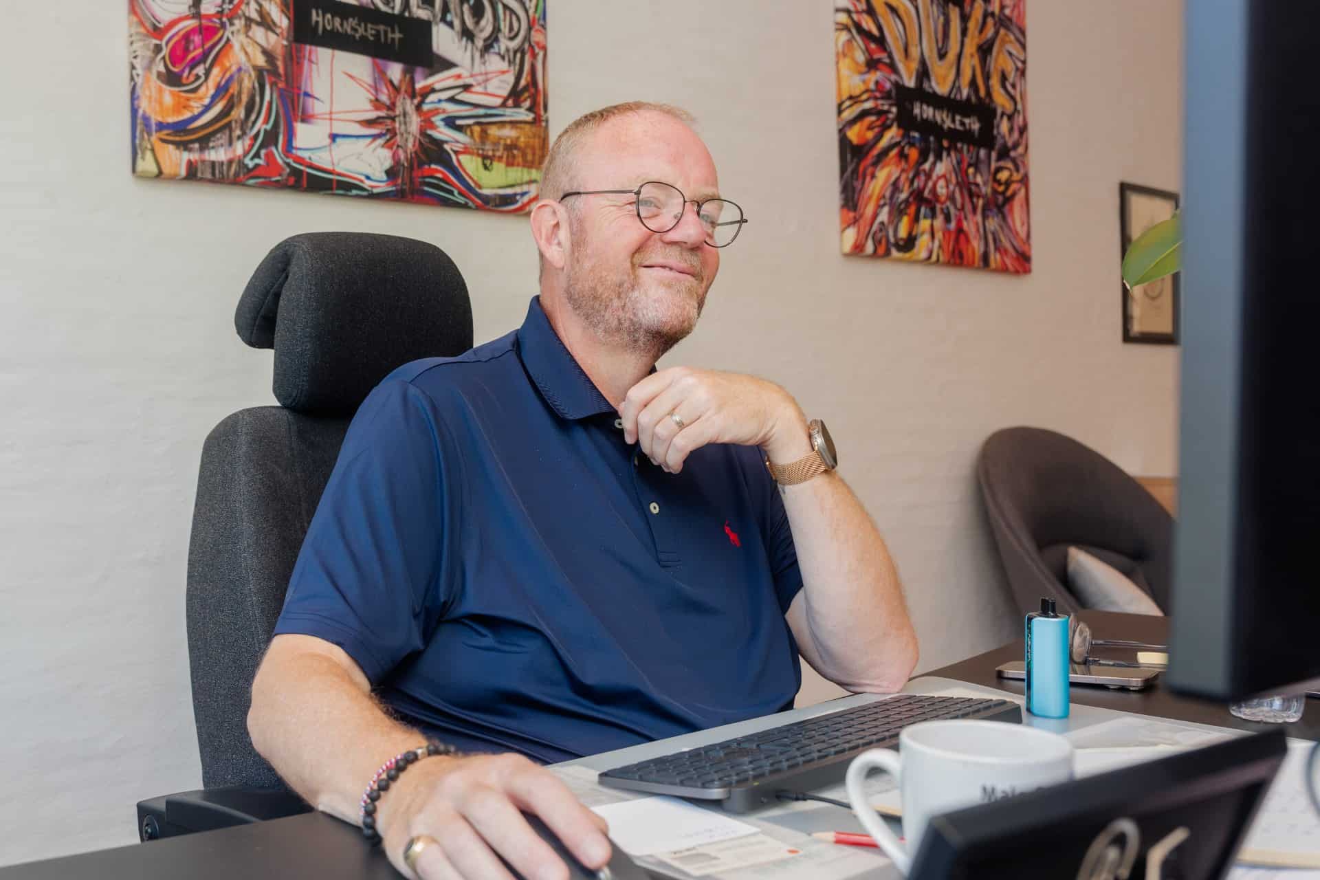 Smilende medarbejder hos Malerfirmaet KL, der sidder på kontoret